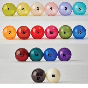 May include: A collection of eighteen numbered, transparent spheres in various colors, including yellow, pink, green, and blue. Each sphere has a number from 1 to 18 printed on it in black. The spheres are arranged in rows.