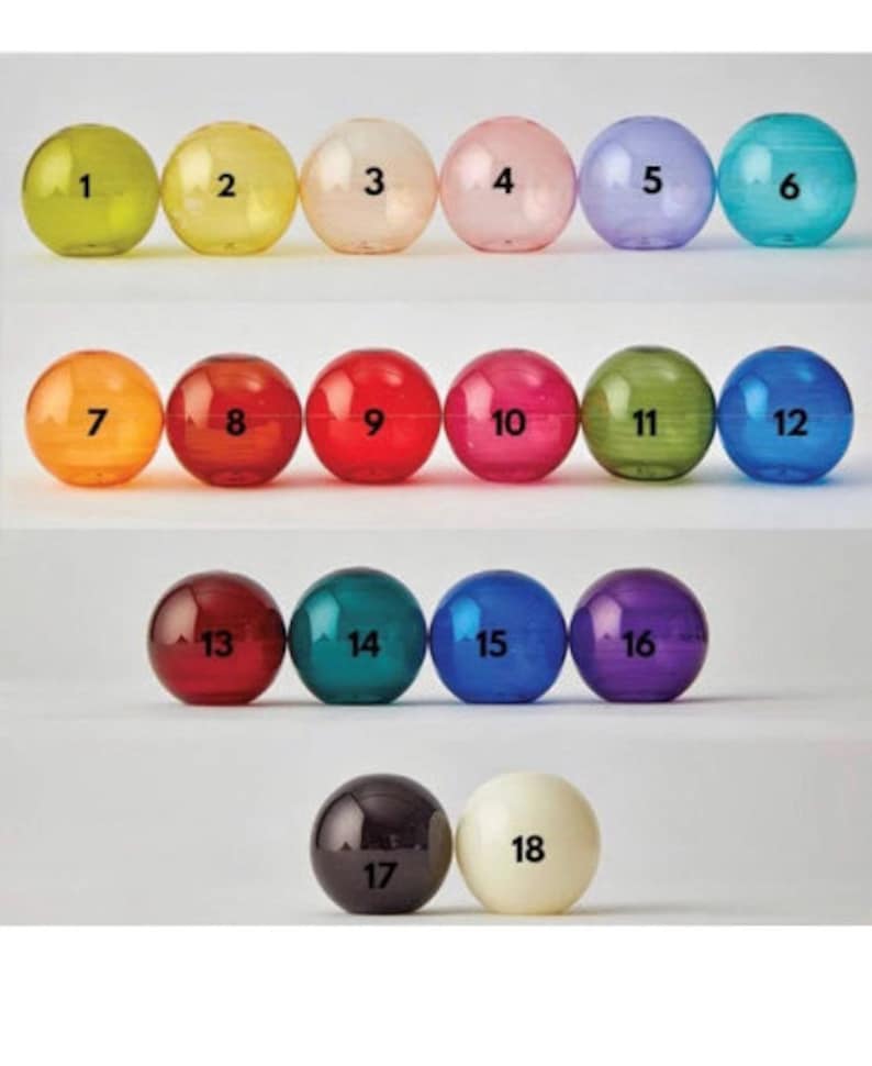 May include: A collection of eighteen numbered, transparent spheres in various colors, including yellow, pink, green, and blue. Each sphere has a number from 1 to 18 printed on it in black. The spheres are arranged in rows.
