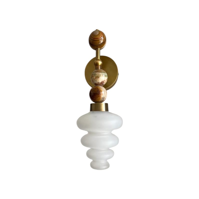 May include: A wall-mounted light fixture with a brass finish and a frosted glass shade. The sconce features decorative stone spheres in brown and green. The light is designed for indoor use and adds a touch of elegance. The overall height is approximately 30 cm.