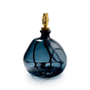 May include: A dark blue glass lamp base with a gold metal socket. The base has a unique, organic shape with a swirling design.