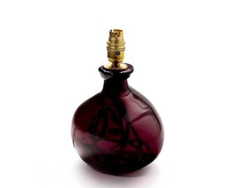May include: A dark purple glass lamp base with a gold metal socket.