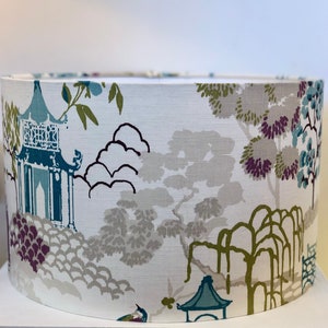 May include: A white lampshade with a blue and green Asian-inspired print featuring trees, pagodas, and clouds.
