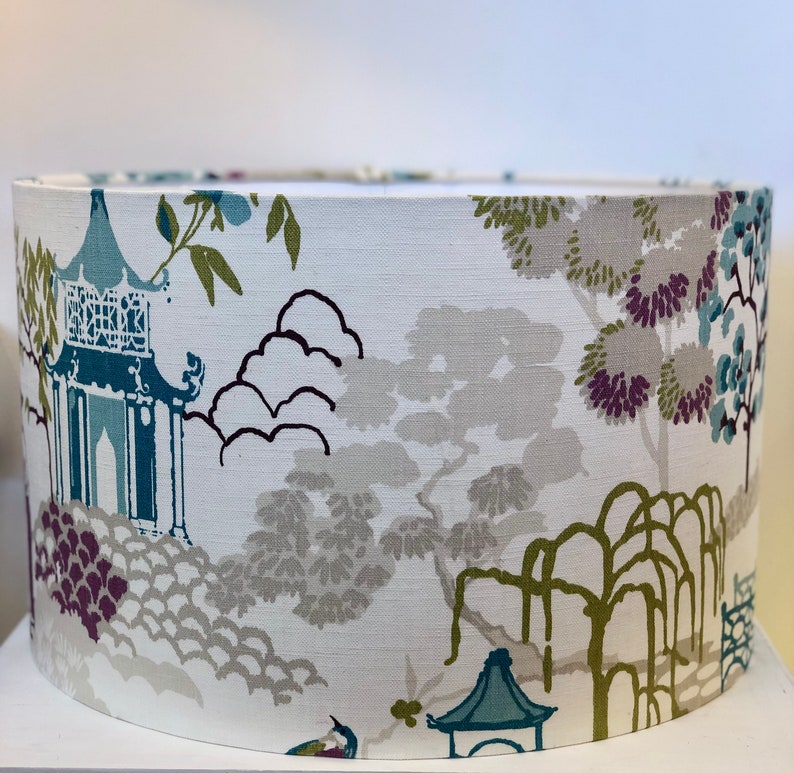 May include: A white lampshade with a blue and green Asian-inspired print featuring trees, pagodas, and clouds.