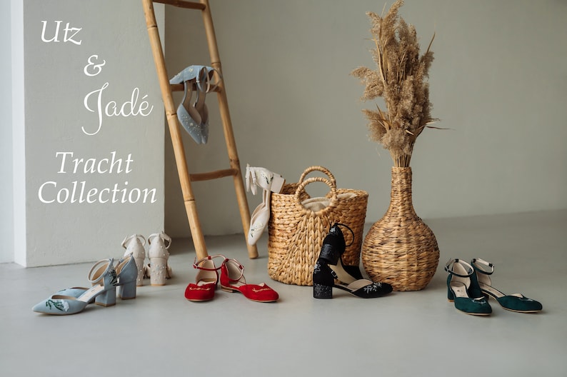 K&ouml;nnte beinhalten: Eine Kollektion von Schuhen in Hellblau, Rot, Schwarz und Dunkelgr&uuml;n mit Kn&ouml;chelriemen und Blockabs&auml;tzen, dazu ein geflochtener Korb und eine hohe Vase mit getrocknetem Gras. Der Text Utz & Jad&eacute; Tracht Collection ist zu sehen.