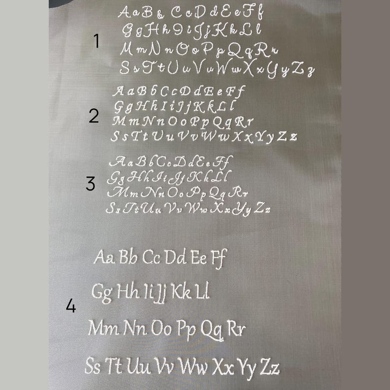 May include: A white fabric with four rows of the alphabet, A through Z, in cursive script. Each row is numbered 1 through 4.