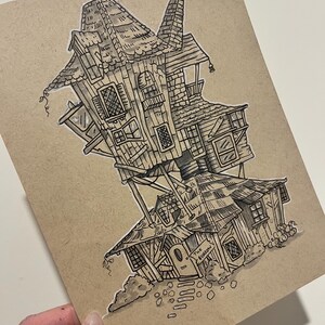 May include: A black and white pen and ink illustration of a whimsical, multi-story house with a slanted design. The house has multiple windows, a chimney, and the text "The Burrow" above the front door. The artwork is on a tan paper.