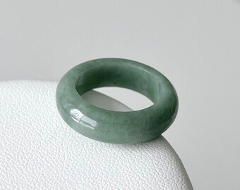 May include: A green jade ring with a smooth, polished finish. The ring is thick and has a rounded shape.