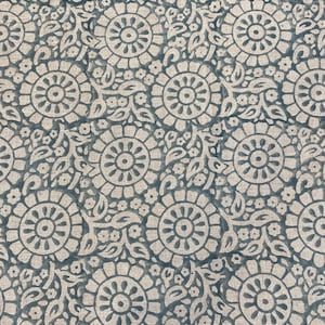 May include: A blue and white fabric with a repeating pattern of stylized flowers. The fabric has a textured surface.