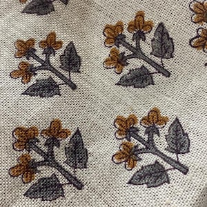 Peut inclure: Un tissu beige avec un motif répété de petites fleurs brunes avec des tiges et des feuilles grises.