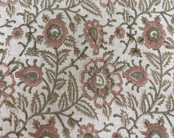 Op de afbeelding: Een beige stof met een herhalend bloemenpatroon. De bloemen zijn roze en groen met een witte omtrek. De stof heeft een subtiele textuur.