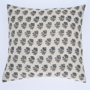 May include: A cream-colored pillow cover with a repeating pattern of blue and brown floral designs.