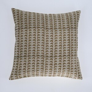 May include: A square throw pillow with a white background and a brown geometric pattern. The pattern is made up of small, repeating shapes that resemble leaves.