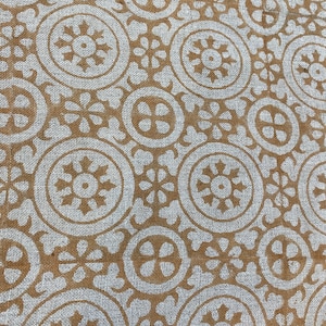 May include: A white fabric with a brown geometric pattern. The pattern is made up of circles, stars, and flowers.