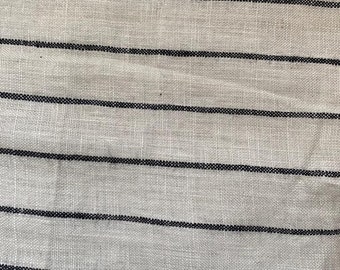 May include: White fabric with thin black stripes. The fabric has a woven texture.