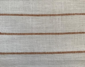 May include: White fabric with thin brown stripes. The fabric has a woven texture.