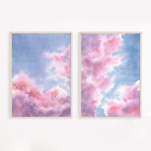 Puede incluir: Dos pinturas de acuarela enmarcadas de nubes rosas y azules. Las pinturas son de estilo moderno y quedar&iacute;an muy bien en una sala de estar o un dormitorio.