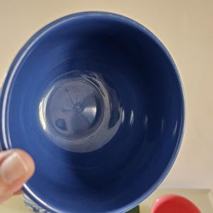 Puede incluir: Un cuenco de cer&aacute;mica azul oscuro con un detalle de rayas blancas. El cuenco es redondo y tiene un acabado liso y brillante. Tambi&eacute;n se ve un cuenco m&aacute;s peque&ntilde;o con el interior rosa.