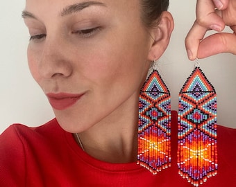 May include: A pair of long, colorful beaded earrings with a geometric pattern. The earrings are made with red, orange, yellow, blue, purple, and black beads.