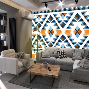Könnte beinhalten: Ein Wohnzimmer mit einem grauen Ecksofa und einem weißen Sessel. Die Wand hinter dem Sofa ist mit einem großen geometrischen Muster in Blautönen, Orange und Weiß verziert. Ein Holz-Couchtisch steht vor dem Sofa.