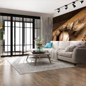 May include: A living room interior with a white sectional sofa, a wooden coffee table, and a rug. The wall behind the sofa features a mural of a baseball glove catching a ball with a bat behind it.