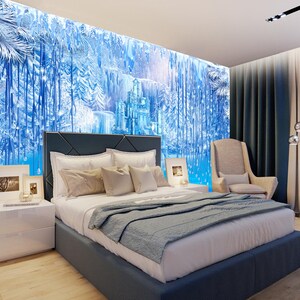 Op de afbeelding: Een slaapkamer met een blauwe en witte muurschildering die een bevroren bos en kasteel voorstelt. Het bed heeft een blauw hoofdeinde en een wit en blauwe deken. Er is een wit nachtkastje met een lamp en een fotolijst erop. Een beige fauteuil staat in de hoek van de kamer.