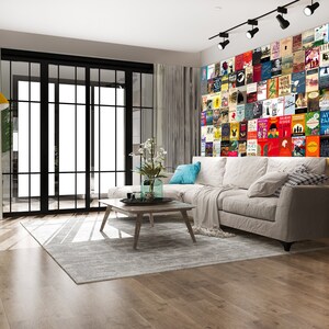 May include: A living room with a white sectional sofa, a coffee table, and a wall covered in book covers. The wall is a colorful collage of book covers, with a variety of genres and authors represented.