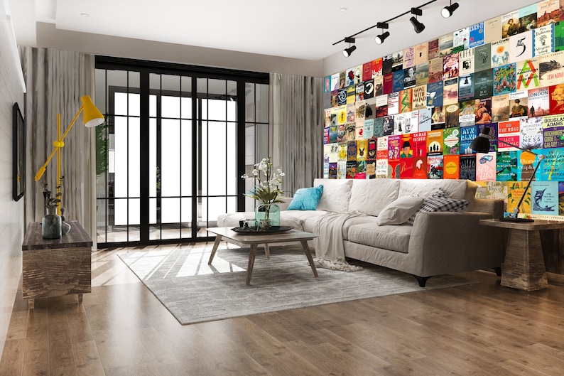 May include: A living room with a white sectional sofa, a coffee table, and a wall covered in book covers. The wall is a colorful collage of book covers, with a variety of genres and authors represented.