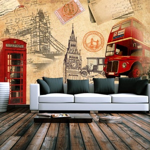 May include: A vintage-style illustration of London landmarks, including Big Ben, a red double-decker bus, a red telephone booth, and Tower Bridge. The illustration is printed on a wall behind a white couch with black pillows.
