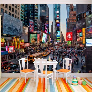May include: A colorful photo mural depicting Times Square in New York City at dusk. The image features bright lights, billboards, and a bustling crowd of people walking on the street. There are yellow taxis and a yellow school bus in the street.