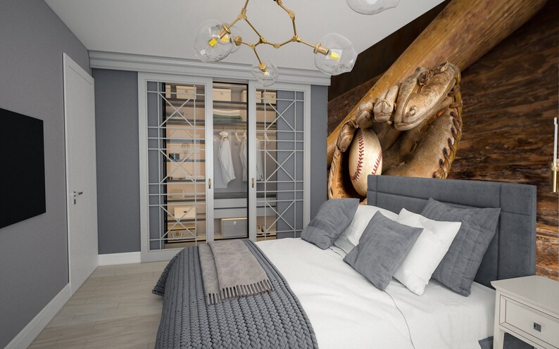 May include: A bedroom decorated in shades of grey and white. The bedroom features a bed with a grey headboard, white bedding, and a grey knitted throw blanket. The wall behind the bed has a mural of a baseball glove catching a baseball. The bedroom also has a wardrobe with glass doors, a bedside table, and a television.