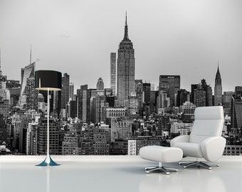May include: Black and white photograph of the New York City skyline, featuring the Empire State Building, with a black floor lamp and two white chairs in the foreground.