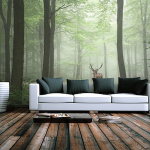 May include: A white couch with black pillows sits in front of a wall mural depicting a foggy forest with a deer standing in the middle.