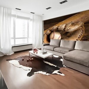 May include: A brown leather baseball glove with a baseball inside, resting on a wooden surface. A wooden baseball bat is behind the glove.