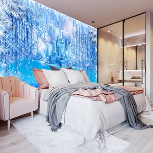 Op de afbeelding: Een slaapkamer met een wit bed, roze kussens en een grijs dekbed. De muur achter het bed heeft een muurschildering van een blauw en wit kasteel in een besneeuwd bos.
