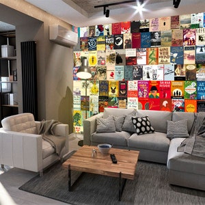 May include: A living room with a gray sectional sofa and a white armchair. The wall behind the sofa is covered in a collage of book covers. A coffee table sits in front of the sofa.