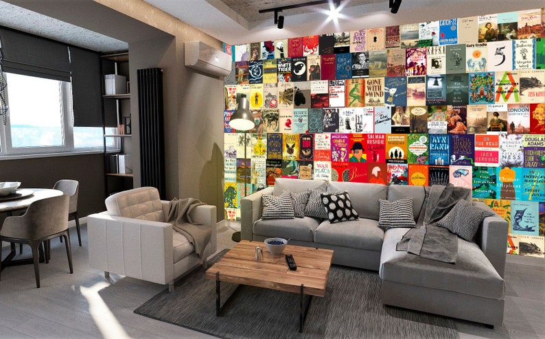 May include: A living room with a gray sectional sofa and a white armchair. The wall behind the sofa is covered in a collage of book covers. A coffee table sits in front of the sofa.