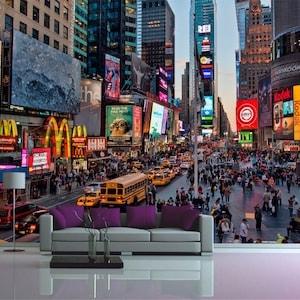 May include: A busy street scene in New York City at night with tall buildings, bright lights, and many people walking around.  There are several billboards with advertisements, including one for a musical called "Ghost".