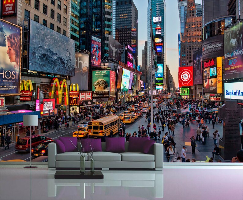 May include: A busy street scene in New York City at night with tall buildings, bright lights, and many people walking around.  There are several billboards with advertisements, including one for a musical called "Ghost".