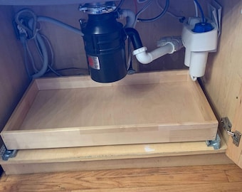 May include: A wooden pull-out drawer under a kitchen sink with a garbage disposal and a water filter.