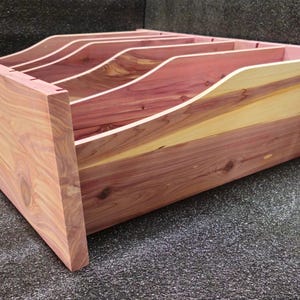 May include: A wooden drawer organizer with five compartments. The organizer is made of cedar wood and has a natural reddish-brown color.