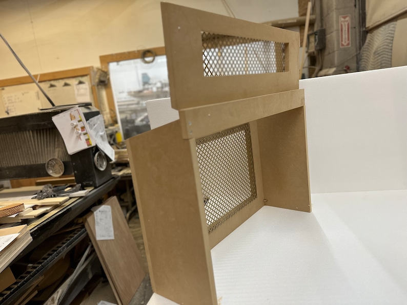 May include: A wooden box with a metal mesh screen on the front. The box is unfinished and has a light brown color.