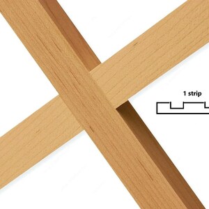 May include: Close-up of a wooden frame with a cross-shaped design. The frame is made of natural wood with a light brown color. The frame is designed to hold a single strip of material, as indicated by the text "1 strip" and a diagram showing a single strip with four evenly spaced notches.