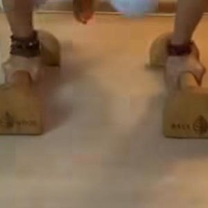 May include: Wooden shoe stretchers with the text "BACK WOOD" and a leaf design. The shoe stretchers are light brown and appear to be made of wood. The shoe stretchers are on a light brown surface.