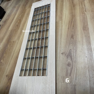 May include: A light wood panel with a metal grate insert. The grate is made of thin metal bars that are spaced evenly apart. The panel is labeled "Screen #6" and "6".