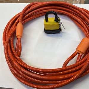 May include: A coiled orange cable with two orange plastic end caps and a yellow padlock with a black body.