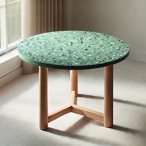 May include: A round side table with a green speckled top and light wood legs. The table has a diameter of approximately 30 inches and stands about 20 inches tall. The legs are connected by a wooden support.