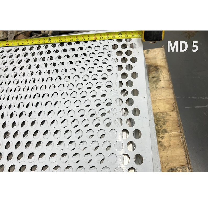 May include: A close-up of a white metal sheet with a pattern of evenly spaced round holes. The sheet is measured with a yellow tape measure, which reads "38". The text "MD 5" is visible in the upper right corner of the image.
