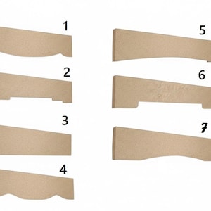 May include: Seven wooden corbels in various designs. Each corbel is a light tan color and has a different decorative edge or shape. The corbels are angled and appear to be for supporting shelves or other architectural elements.