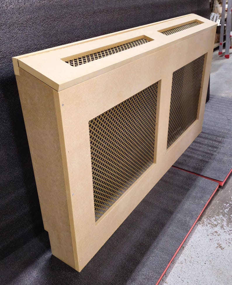 May include: A light brown wooden radiator cover with two rectangular openings covered with a metal mesh grille. The cover is angled to the right.