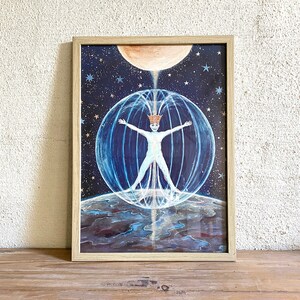May include: A framed painting of a person in a crown standing in a sphere of light with their arms outstretched. The person is surrounded by stars and a moon. The painting is on a wooden surface.